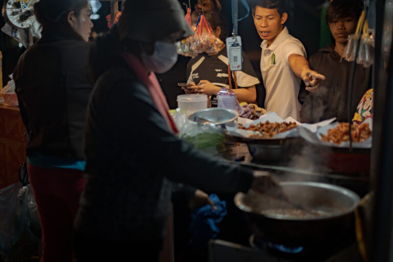 Local chef selecting Cambodian street food at a Siem Reap night market