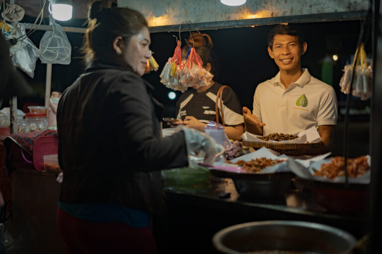 Tour leader buying insect snacks at a local night market in Siem Reap
